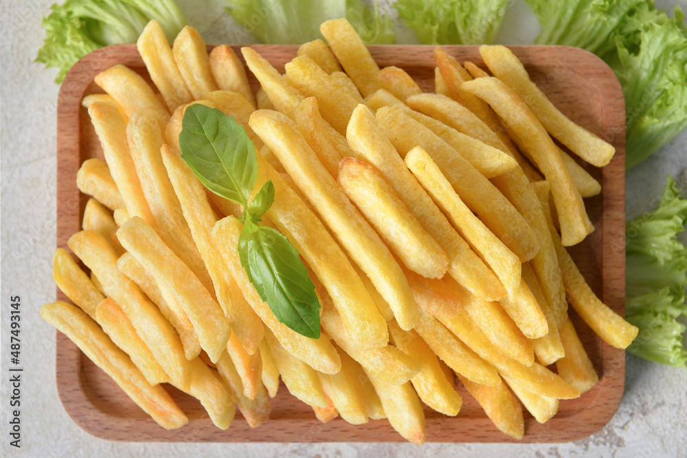 Wooden board with tasty french fries on table