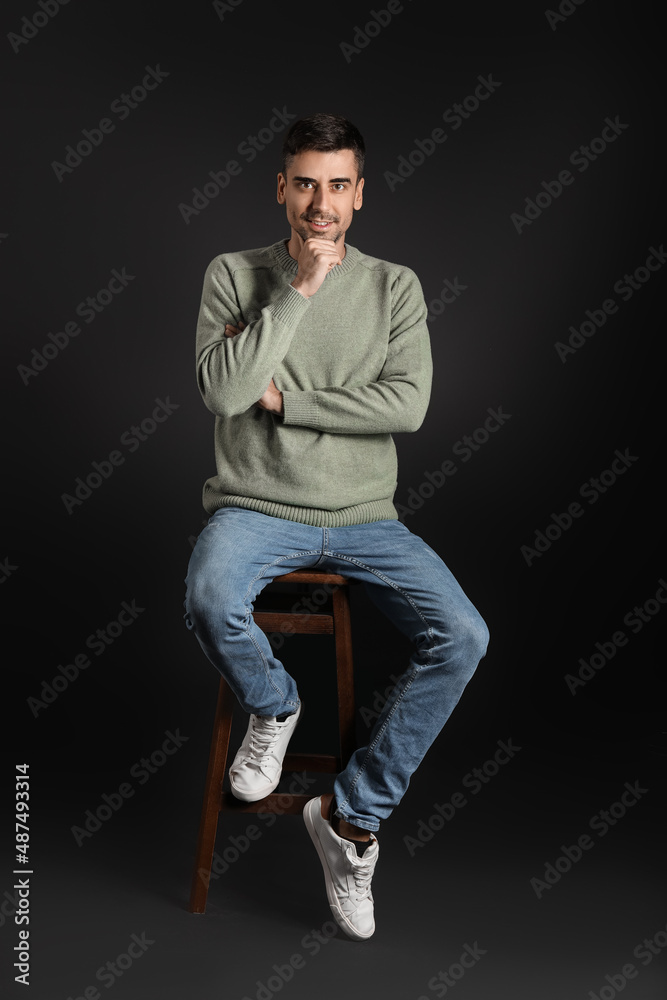 Handsome young man in knitted sweater on dark background