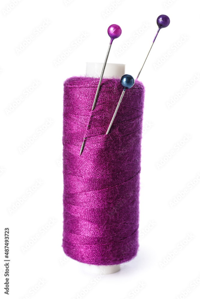 Purple sewing thread spool with needles on white background