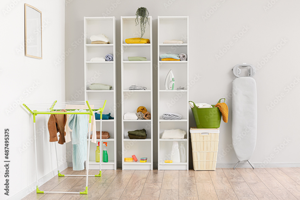 Interior of laundry room with dryer, shelf units, baskets and board