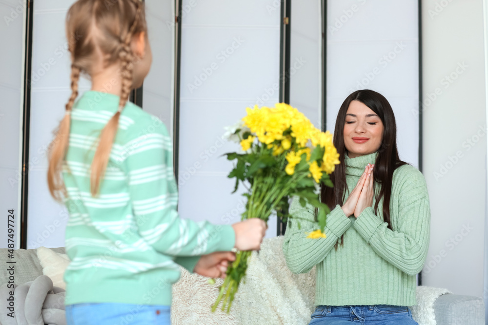 Little girl in warm sweater with flowers for her mother at home