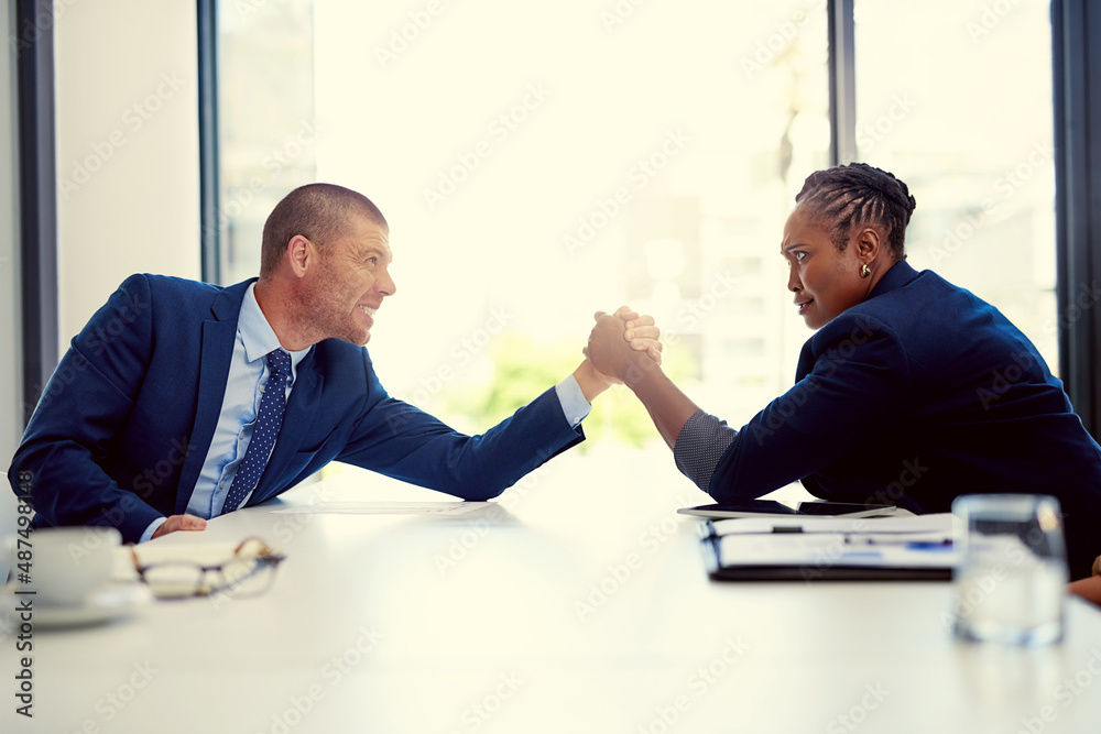 The challenge is on. Shot of two businesspeople arm wrestling in an office.