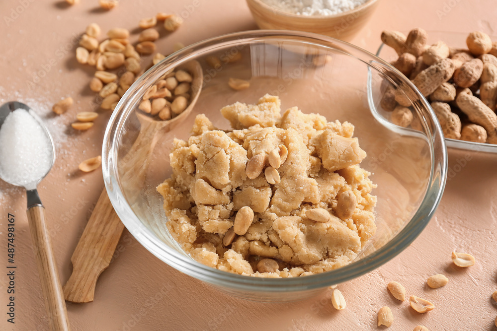 Bowl with fresh dough for preparing peanut cookies on beige background