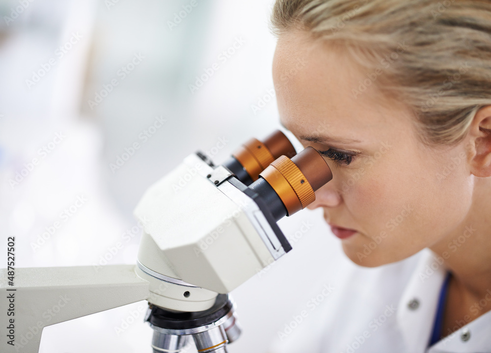 Discover a brand new world. Shot of a beautiful woman in a laboratory working with a microscope.