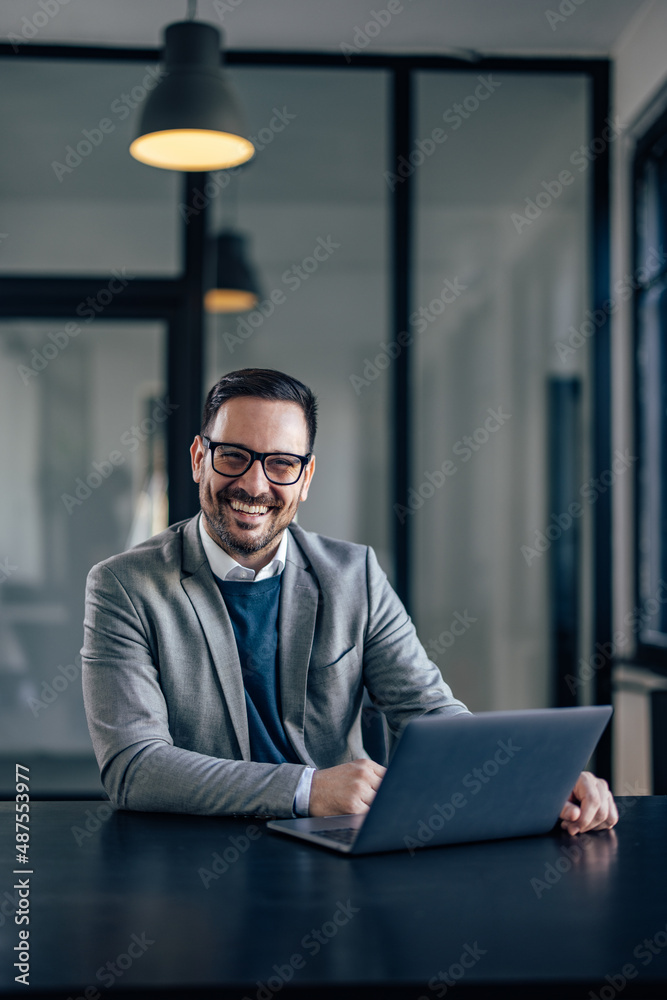 Portrait of happy caucasian man, smiling for the camera while working in the office.