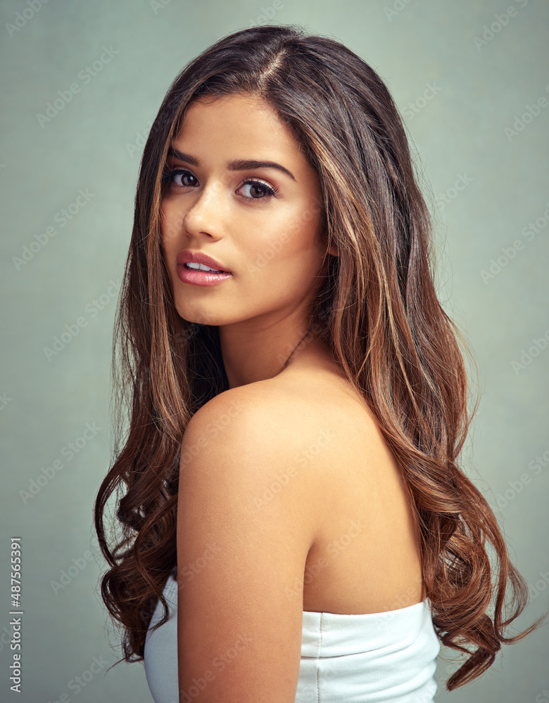 Take care of your hair. Studio portrait of a beautiful woman with long locks posing against a grey b