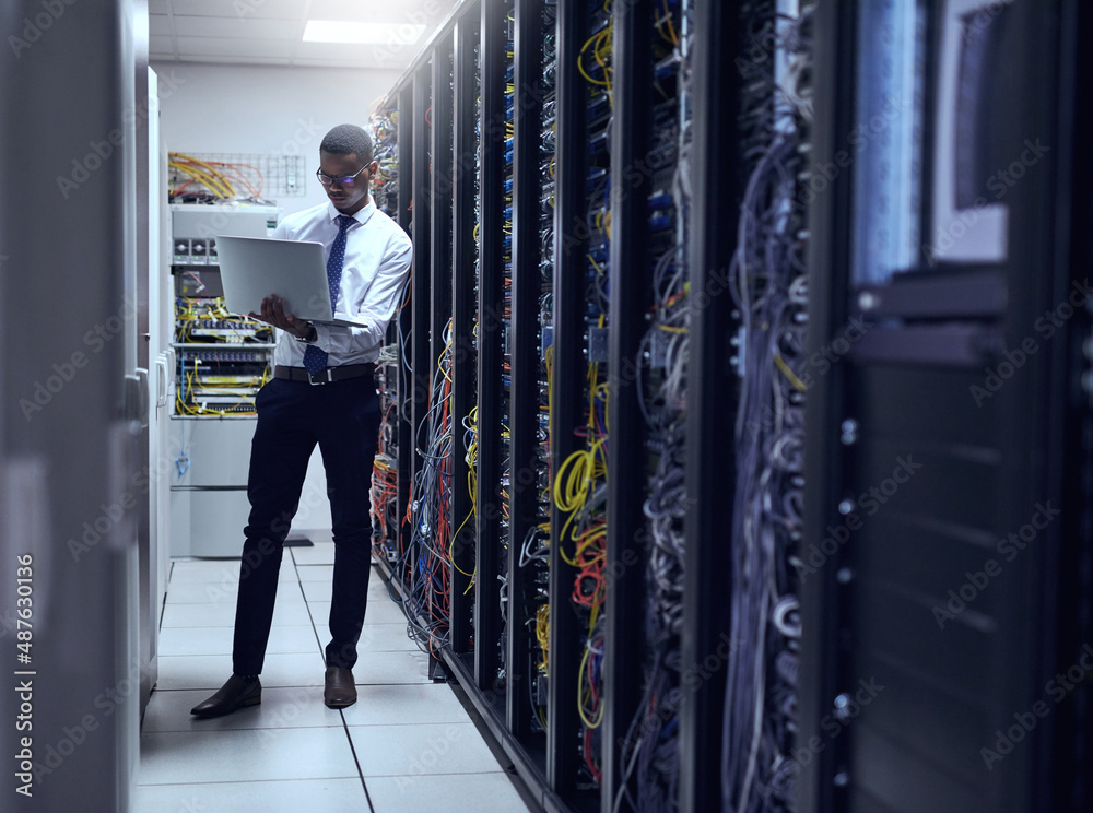 Every calculation counts. Cropped shot of a IT technician working on his laptop while standing insid