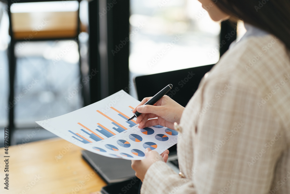 Serious focused businesswoman typing on laptop holding papers preparing report analyzing work result