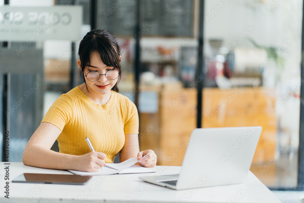 Portrait of charming woman looking at camera during studying on laptop at coworking space, beautiful