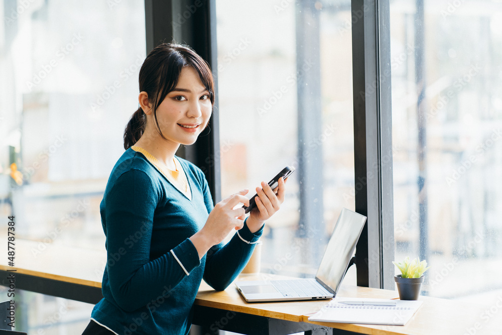 Young happy female reading good news on her mobile phone while sitting in modern coffee shop interio