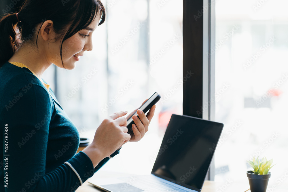 Young happy female reading good news on her mobile phone while sitting in modern coffee shop interio