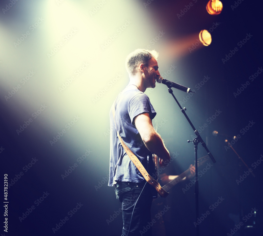 Music from the heart. Shot of a solitary musician playing guitar and singing into a mic.