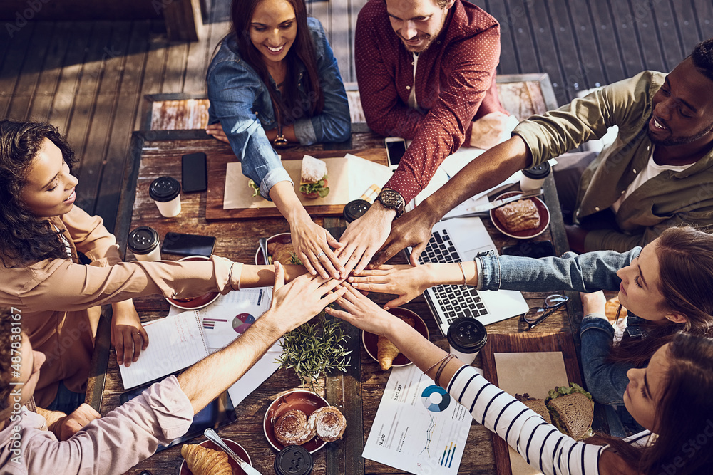 Food inspires everyone. High angle shot of a group of creative workers piling their hands while out 