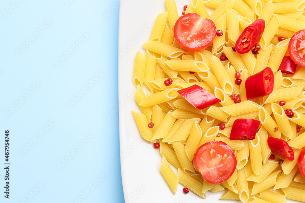 Penne pasta with hot chili peppers on blue background