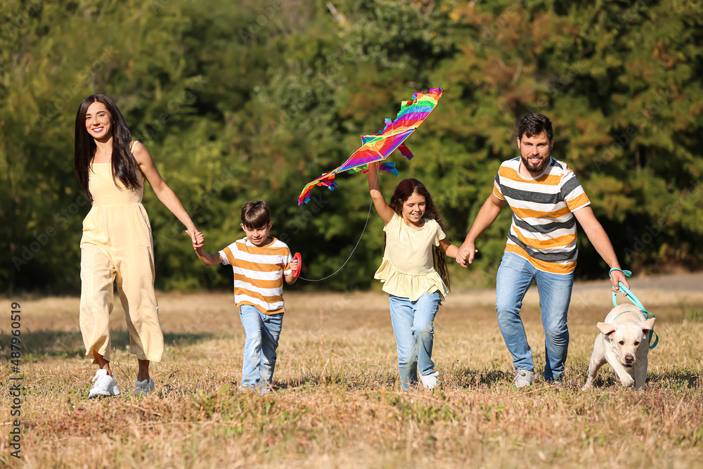 Happy family with cute dog and kite running outdoors