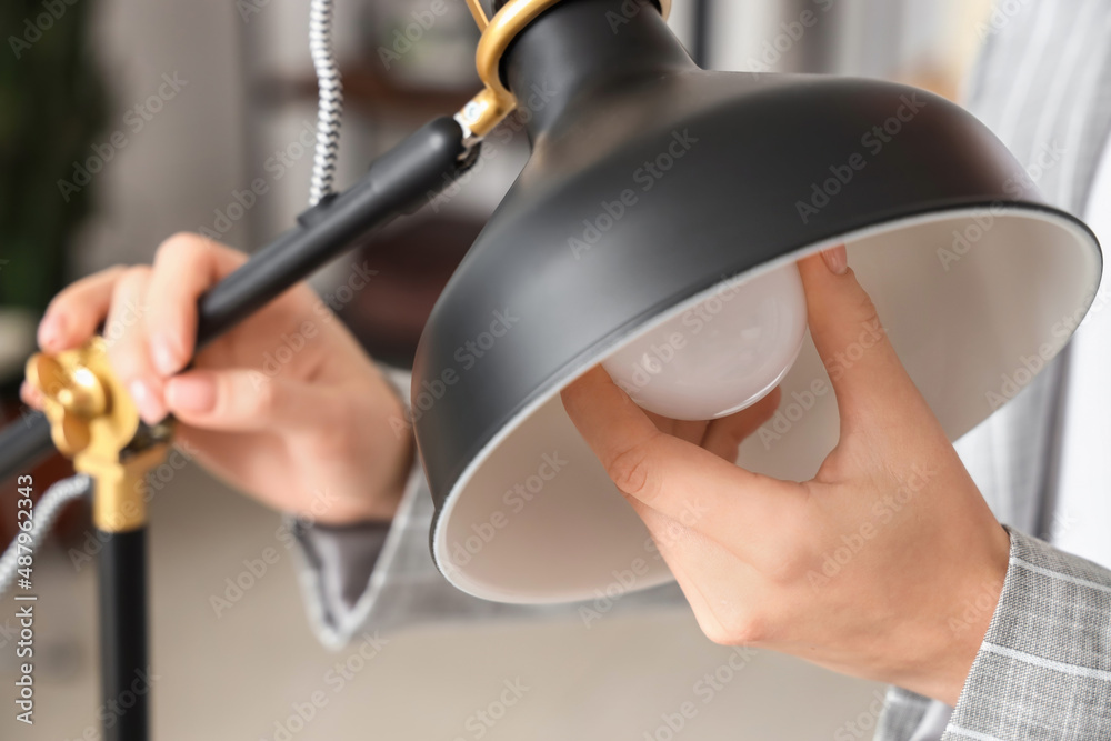 Woman changing light bulb in office lamp, closeup