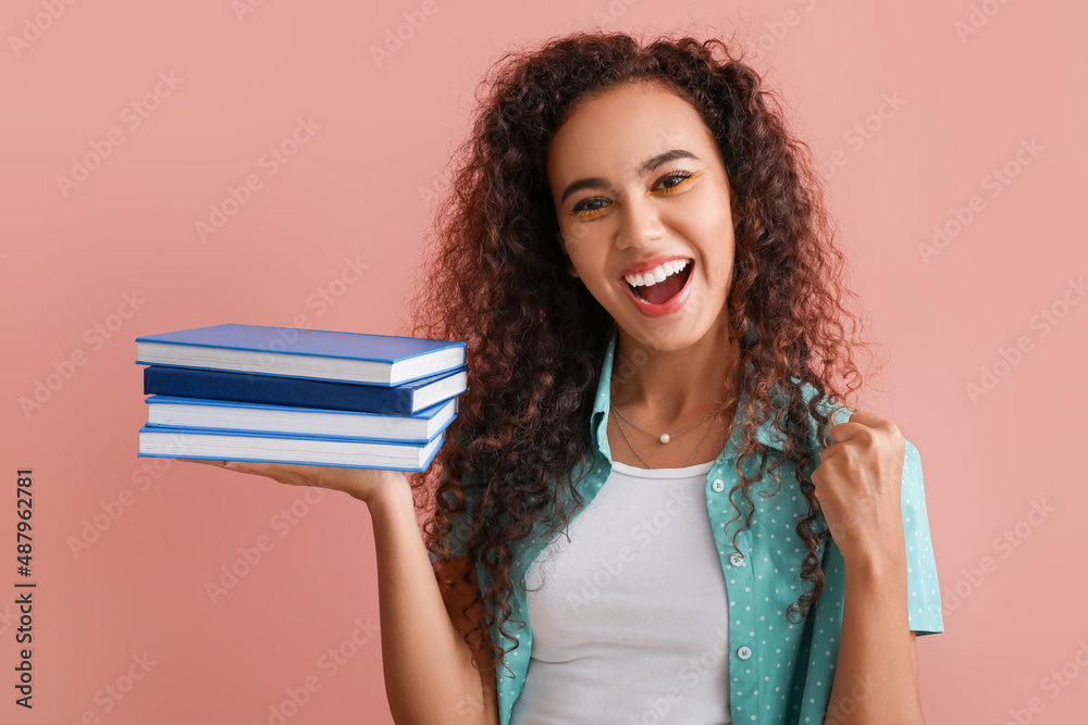 Beautiful young African-American woman with books on color background