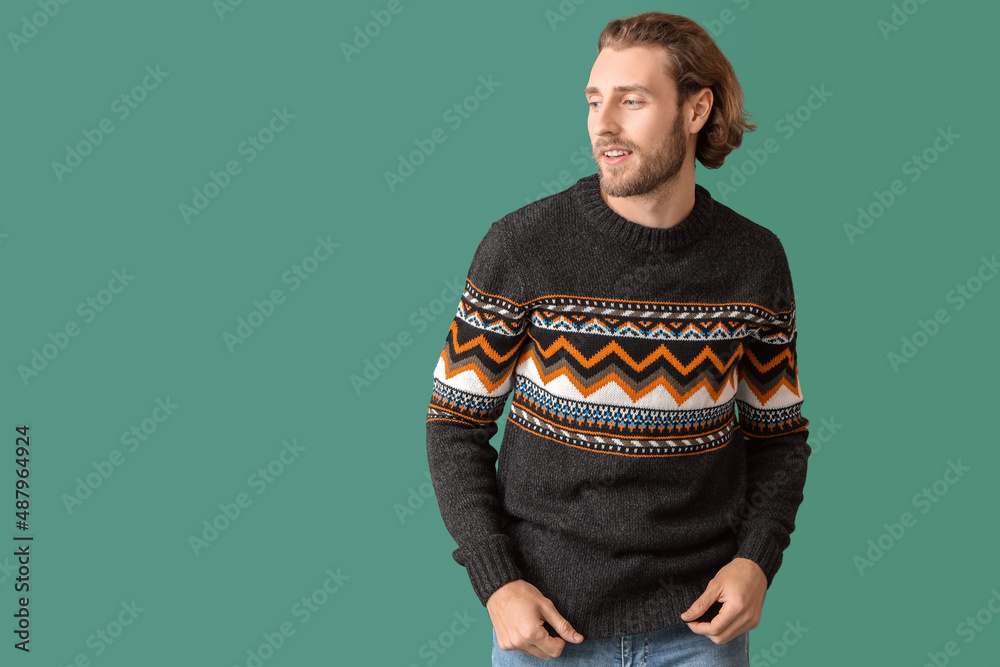 Handsome young man in knitted sweater on color background