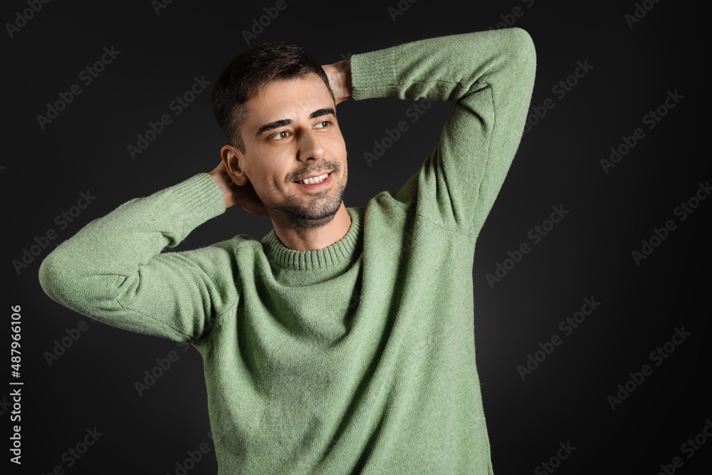 Handsome young man in knitted sweater on dark background