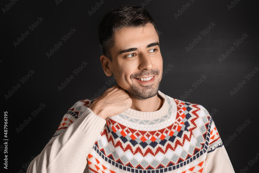 Handsome young man in knitted sweater on dark background