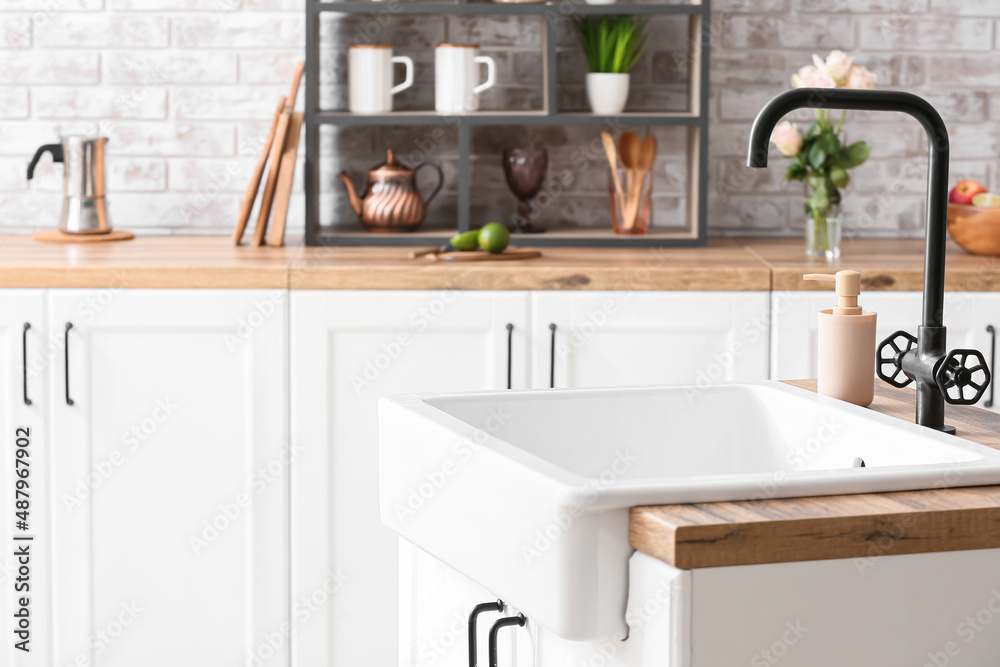 Wooden counter with ceramic sink and dish wash detergent in kitchen