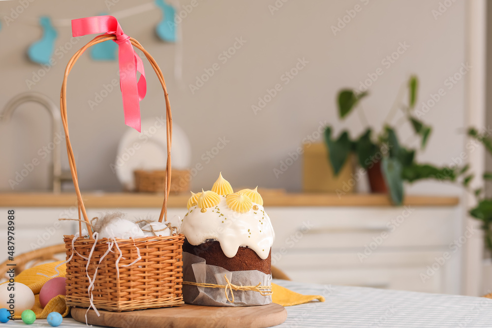 Tasty Easter cakes, basket and eggs on table in kitchen