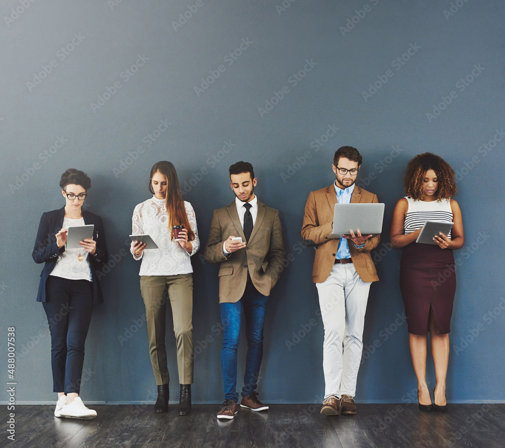 Waiting it out in the name of success. Studio shot of a group of businesspeople using wireless techn