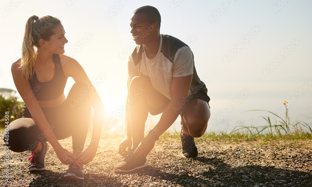 Grab your workout buddy and go. Shot of a fit young couple tying their shoelaces before a run outdoo