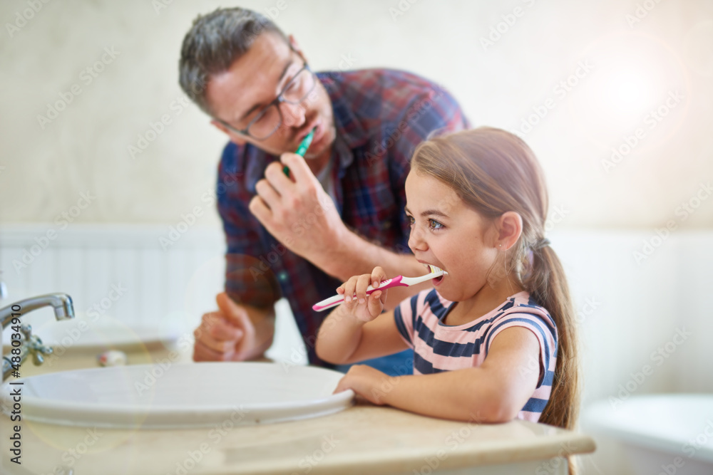 她知道刷牙有多重要。一张父亲和女儿刷牙的照片