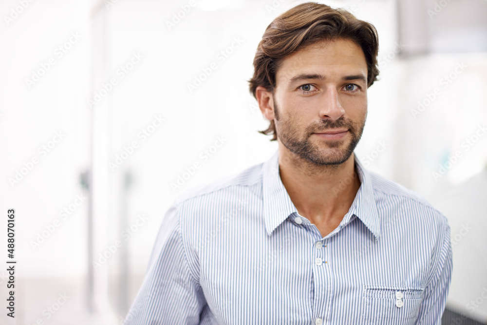 Hes a confident young businessman. Portrait of a handsome young businessman standing in his office.