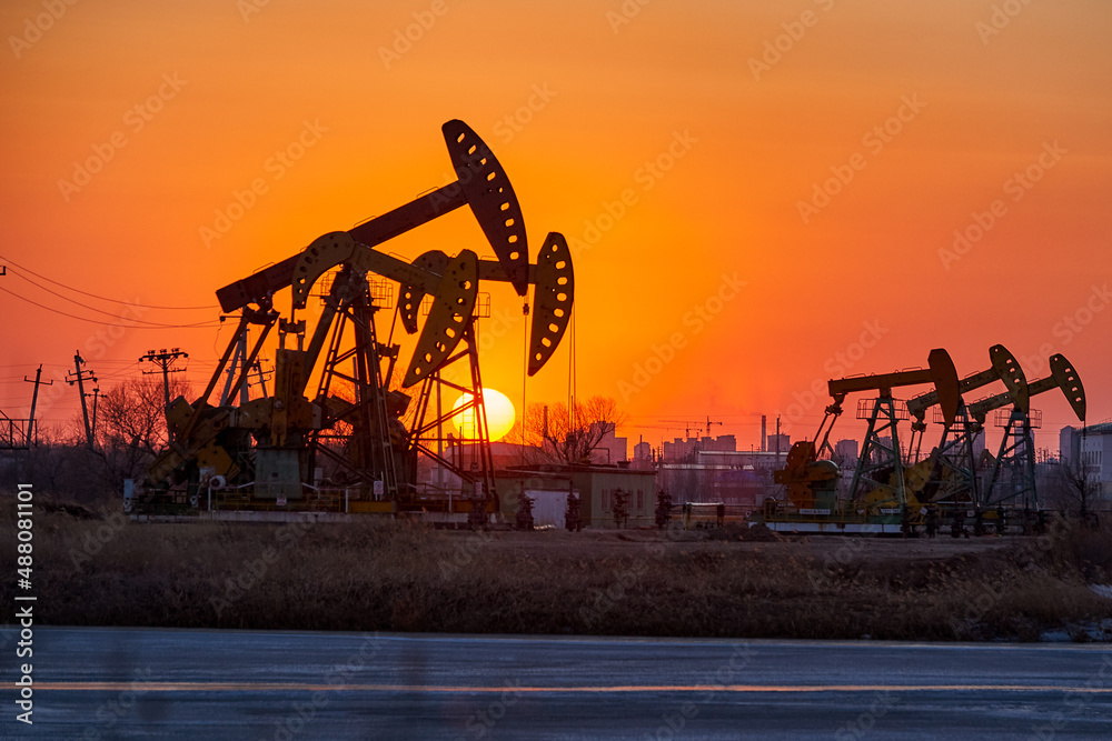 The  oil sucking machines at lakeside sunrise in Daqing oil fields, China.