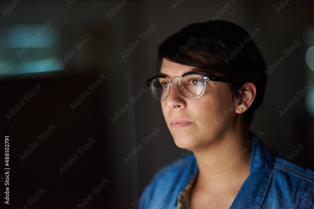 Working late to complete her assignment. Cropped shot of a young woman working late in her office.