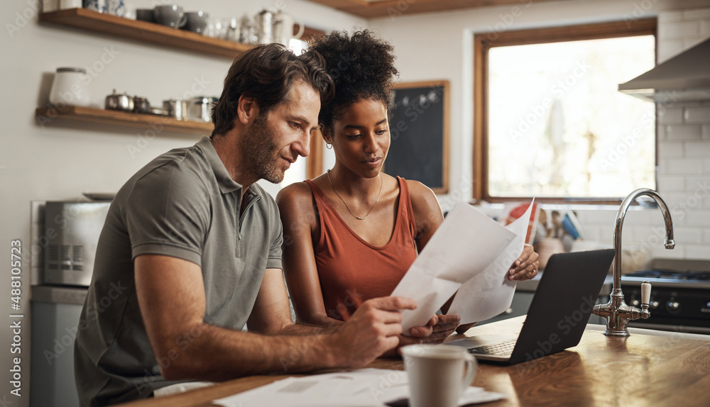 Our debt is almost paid off. Cropped shot of a couple using their laptop and going through paperwork