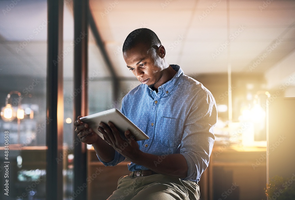 In make things happen mode. Shot of a young businessman using a digital tablet during a late night i