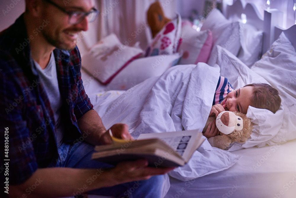 Just one more story daddy. Shot of a father reading a bedtime story to his daughter.