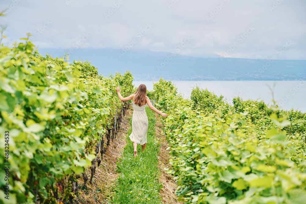 Outdoor landscape portrait of young girl walking in vineyards, wearing long green, dress, back view