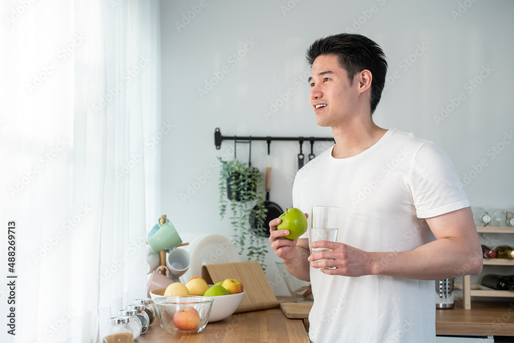 亚洲有魅力的年轻男性在家里的厨房里吃健康食品。