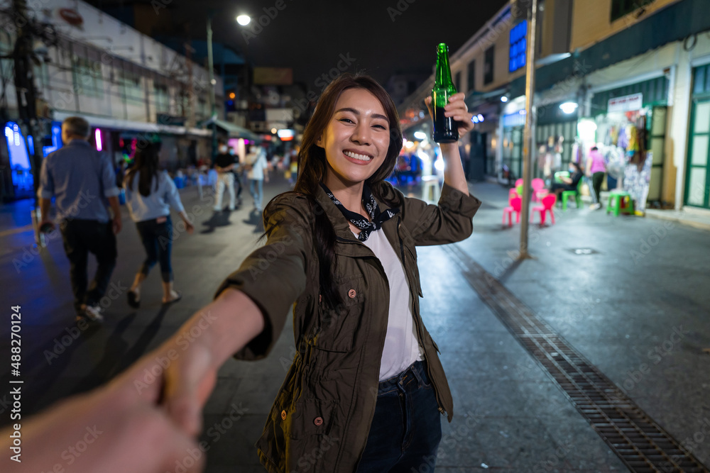 亚洲女旅行者的肖像，牵着男朋友的手，走在街上。