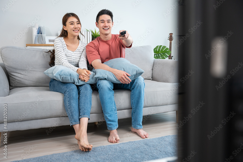 Asian young loving couple watch movie together in living room at home.