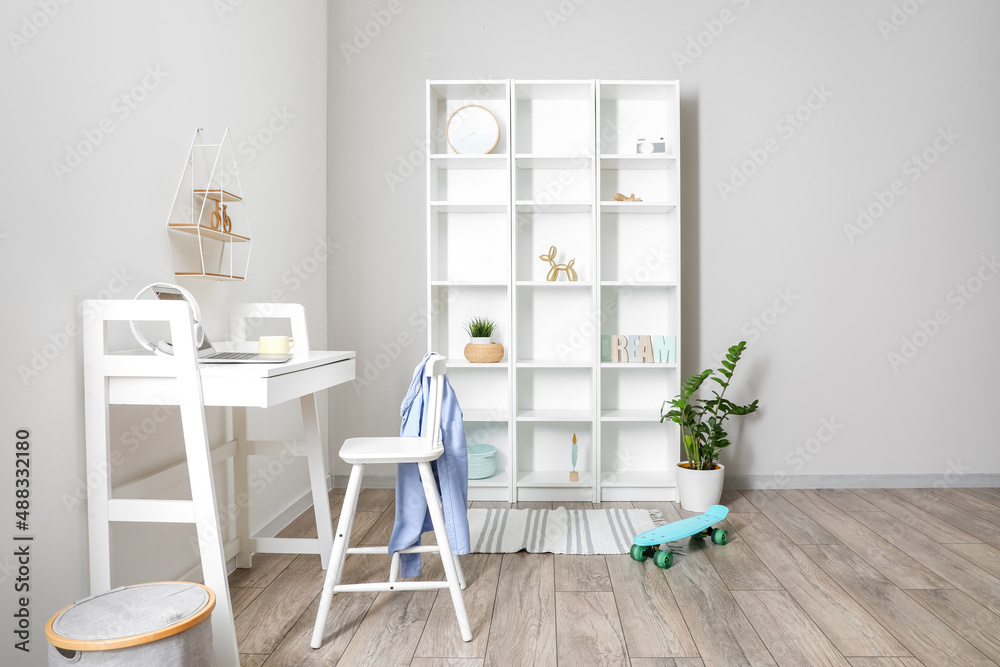 Interior of light room with modern workplace and big shelving unit