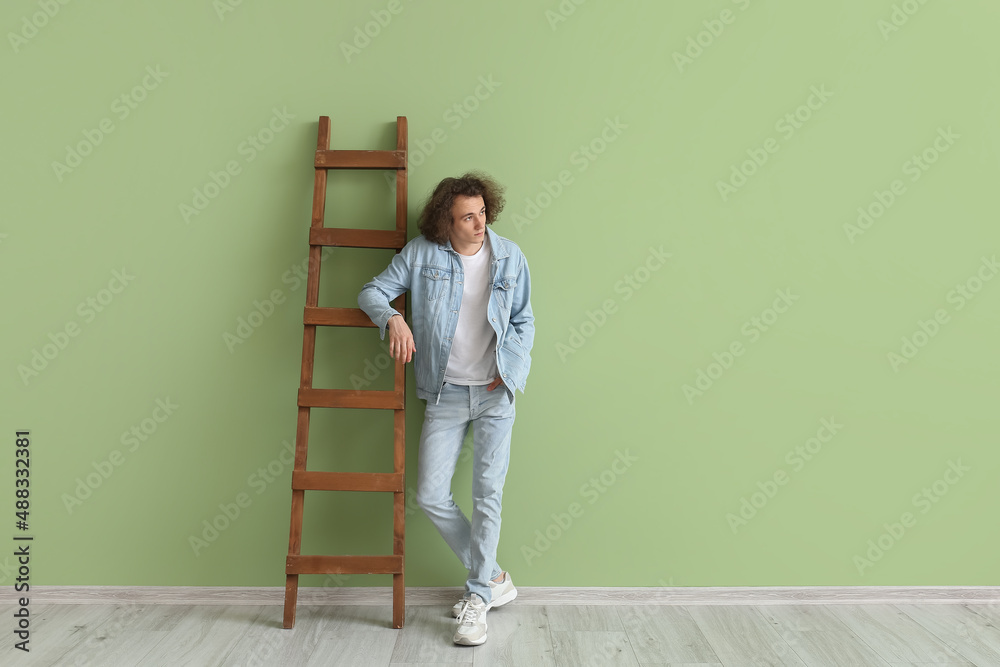 Fashionable young man in stylish jeans clothes near color wall