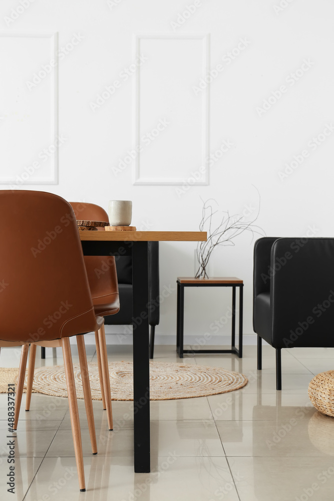 Interior of light dining room with table and black armchairs