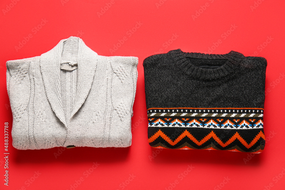 Different stylish sweaters on red background