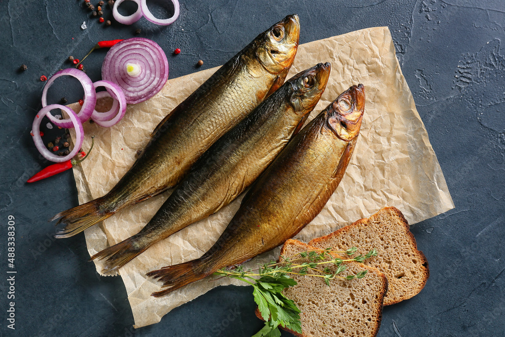 Smoked herring fishes and bread on black background