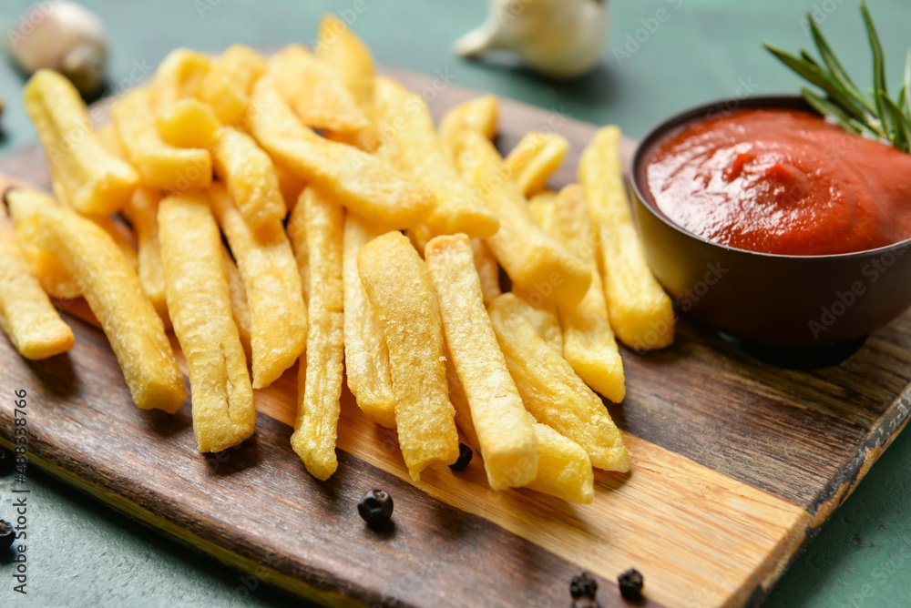 Wooden board with tasty french fries and ketchup on table, closeup