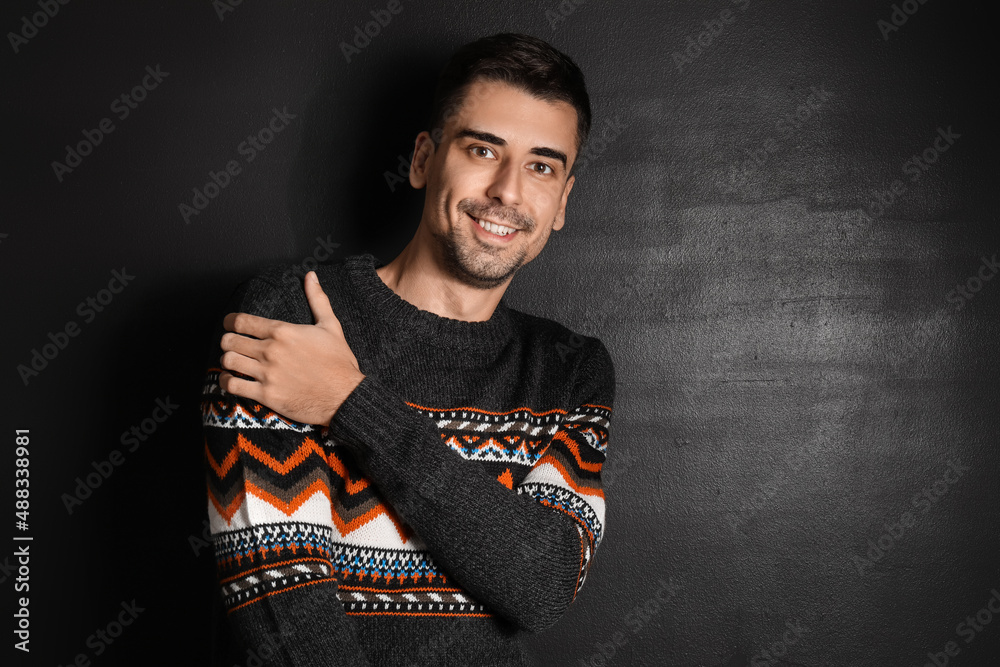 Handsome young man in knitted sweater on dark background