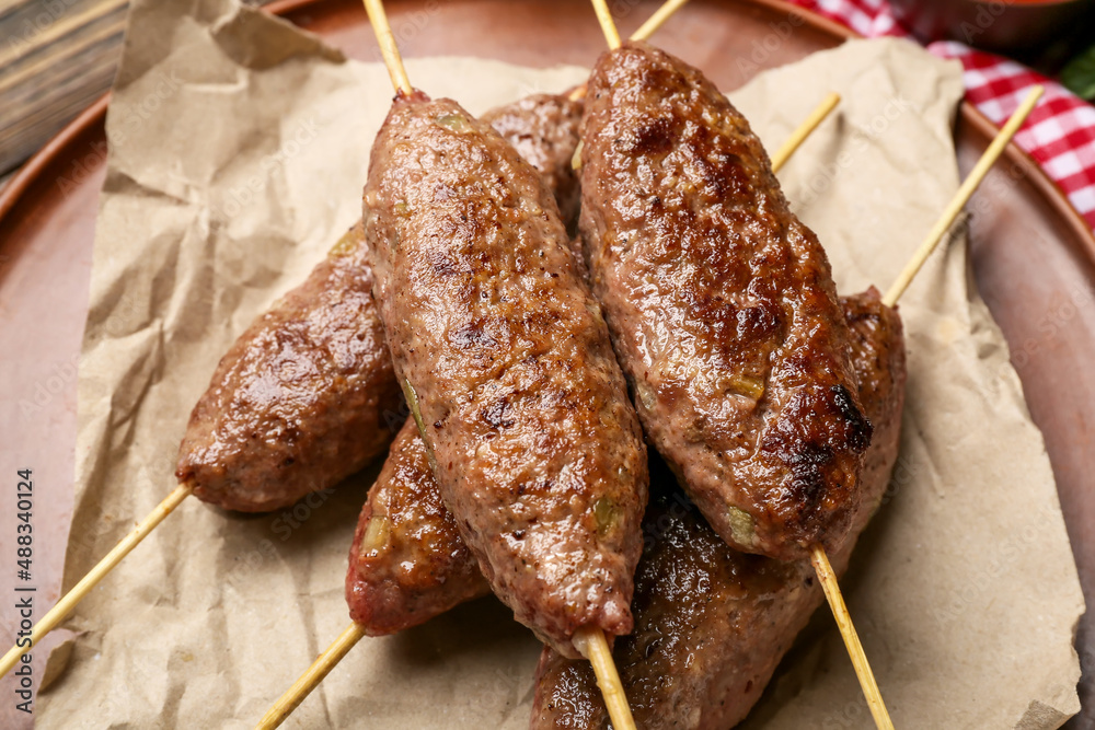 Plate of skewers with tasty lula kebab on table, closeup