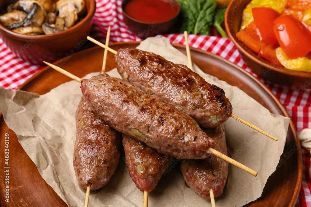 Plate of skewers with tasty lula kebab on table