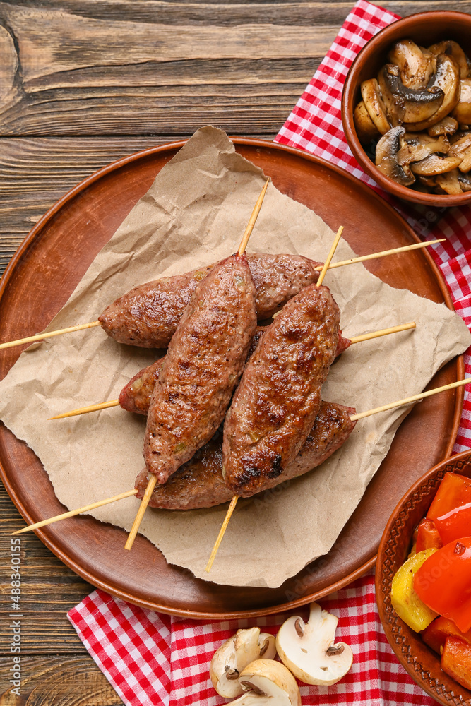 Plate of skewers with tasty lula kebab on wooden background