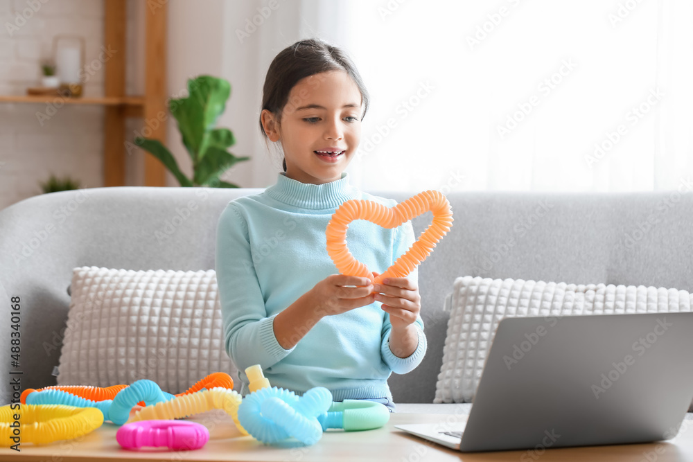 Little girl playing with orange Pop Tube at home